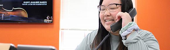 Image of student answering a phone in an office setting.
